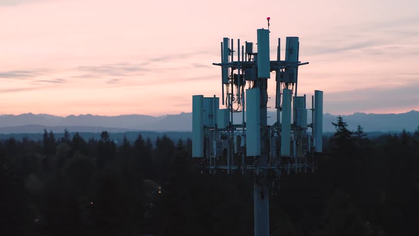 Close up counterclockwise orbit around the top array of a new 5G communications tower working in beautiful soft light