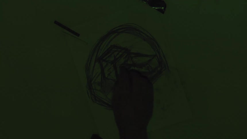 A hand sketches a dark abstract shape on white paper using charcoal