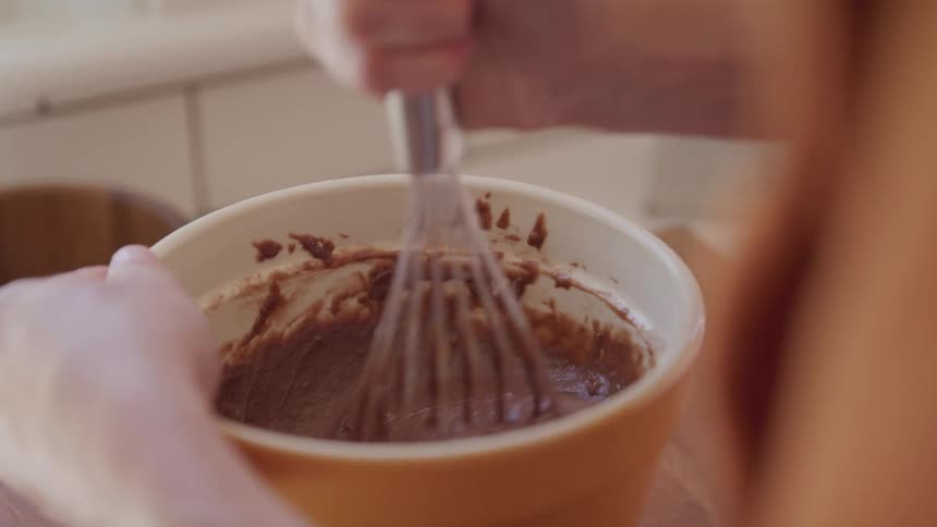 Whisking chocolate batter in an orange bowl