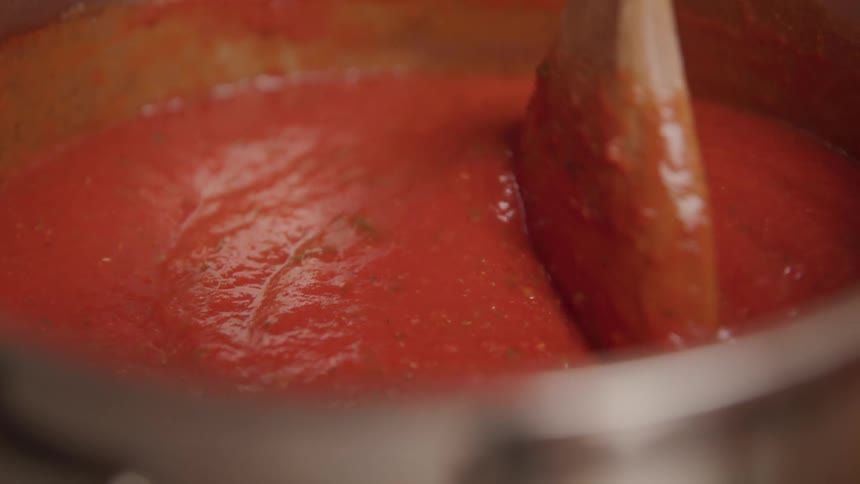 A spoon stirring a pot of sauce