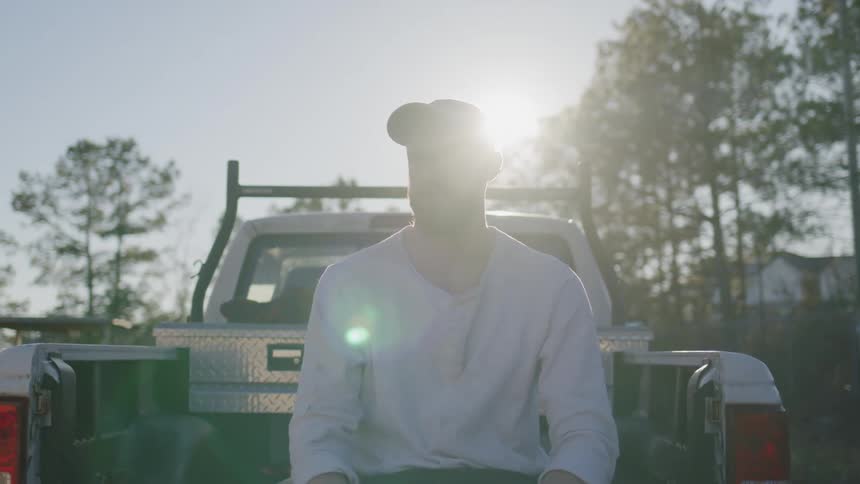 Close up portrait of a man sitting at the back of his truck outdoors during daytime