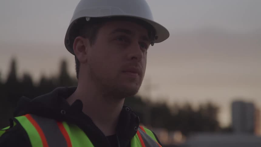Construction worker employee is outdoors while the sun is setting