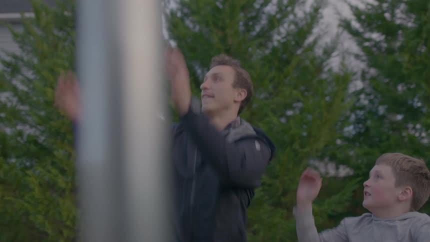 A father and his son playfully jump and compete for a basketball during a game in their backyard