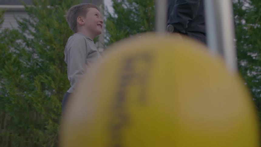 A father and son are talking by the tetherball