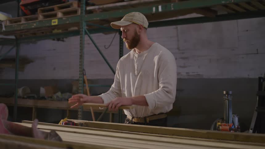 Man rubs and shapes a piece of wood in a workshop