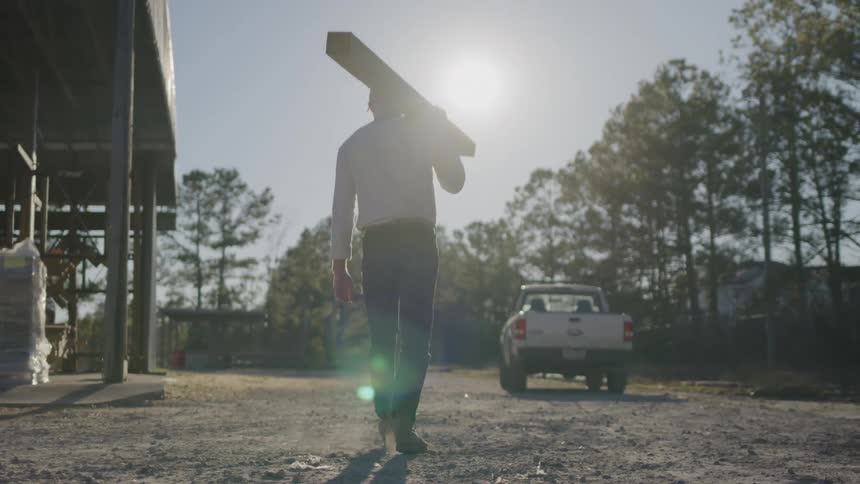 A man carries lumber to his truck