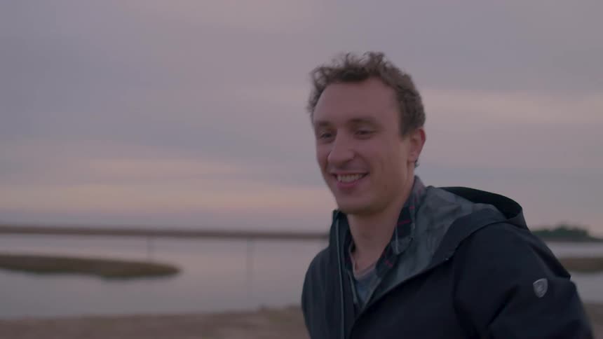 A man happily playing baseball on the coast during sunset