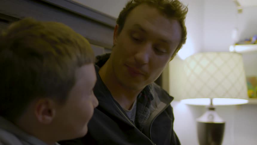 A father and son share a warm conversation in a softly lit room