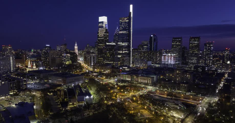 A glowing Philadelphia skyline shines under a deep blue night sky