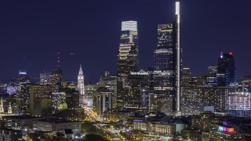A Philadelphia skyline view at night filled with highrise buildings and skyscrapers illuminated against the dark sky