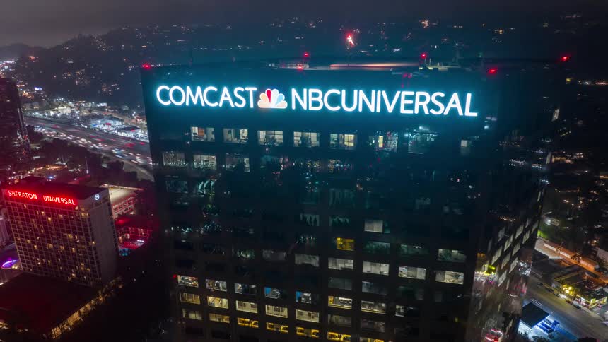 A drone hyperlapse in Universal City Los Angeles showing the Comcast sign on top of a tall building in the city