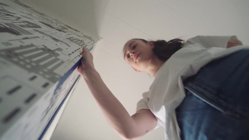 Point of view woman securing blue tape down corner of an interior wall