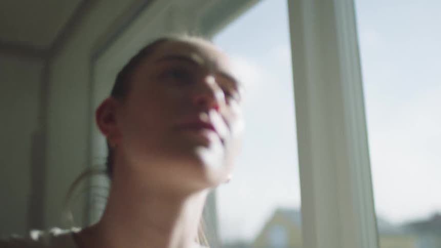 Close up of a woman painting a room wall close to a window during daytime