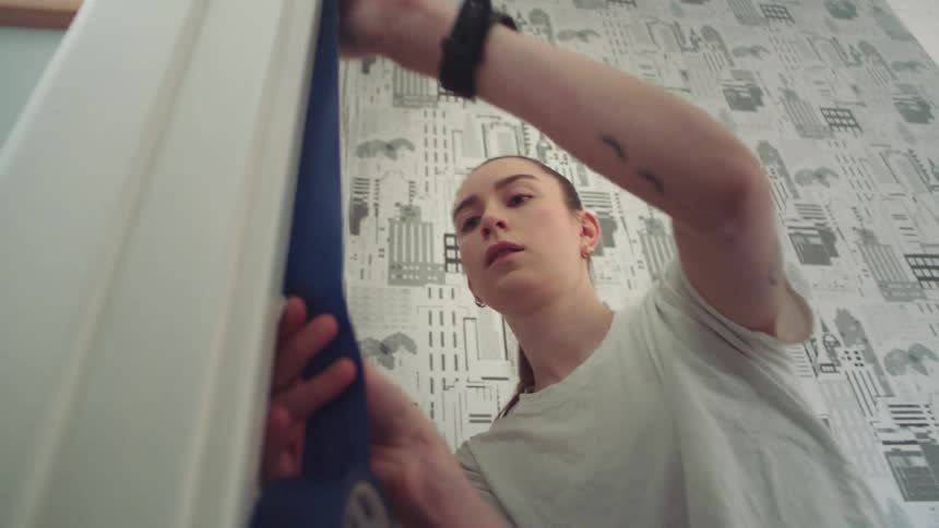 A woman is taping off the wall before painting