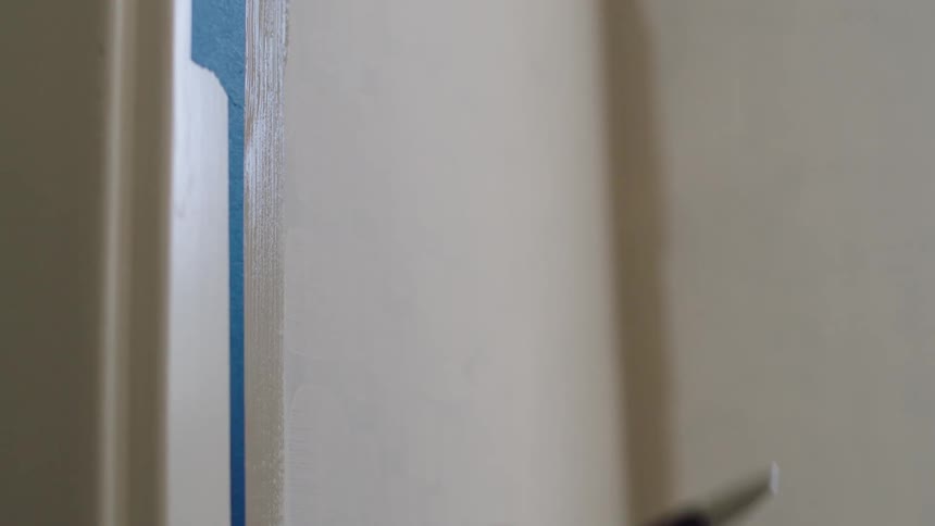 A person paints the door frame