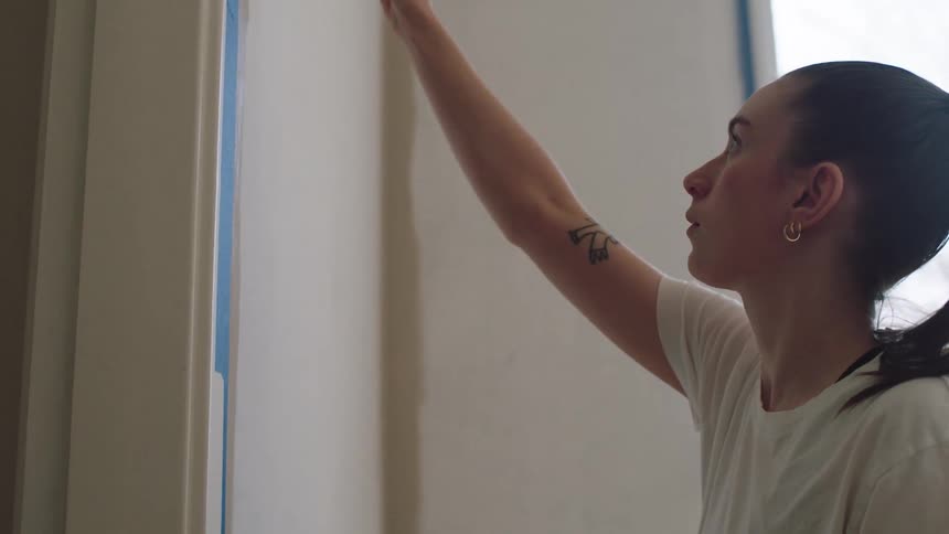Woman is painting the walls inside of her new house