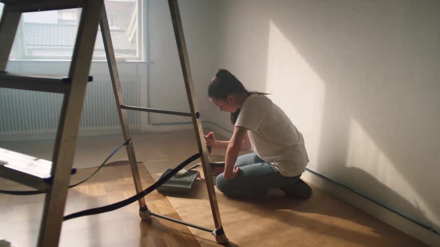 A woman stirring paint in a can getting ready to paint a room