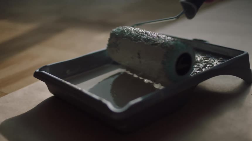 A woman is covering her paint brush with light colored paint
