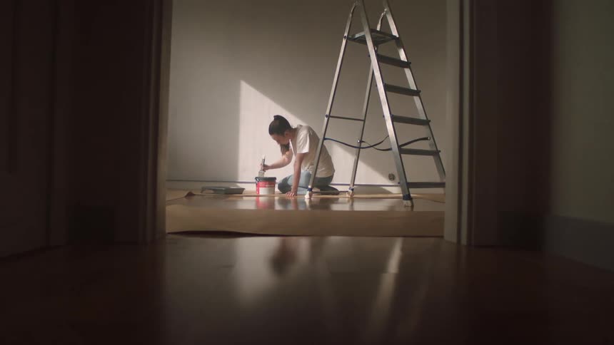 A woman is mixing paint by the ladder