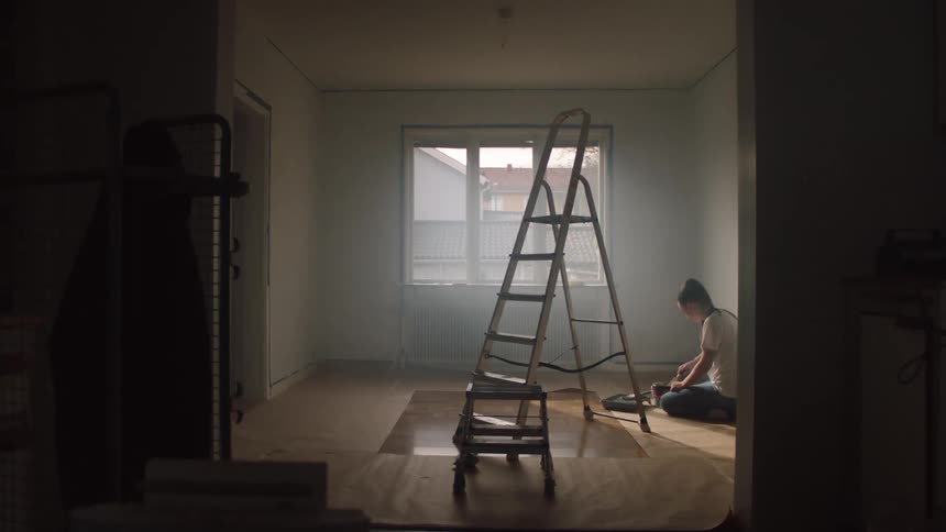 The woman is sitting and dipping her brush into the paint pan