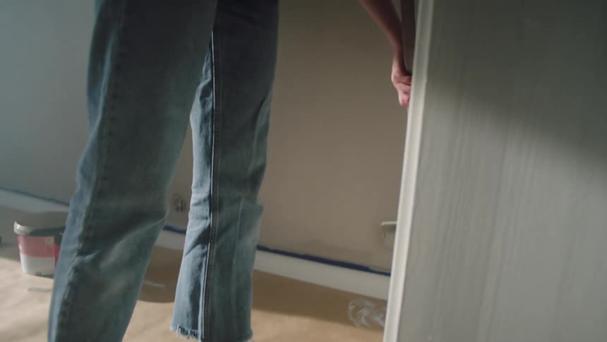 A woman runs the roller with paint on the wall