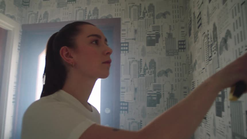 The woman is applying spackle on the wall