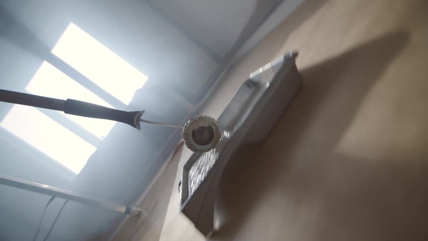 A paint roller applies paint to a wall