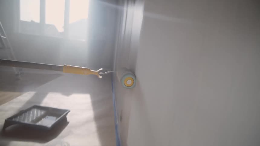 The paint roller spins as it paints the wall
