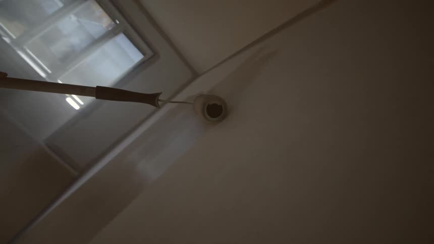 The paint roller is being moved over the whole wall