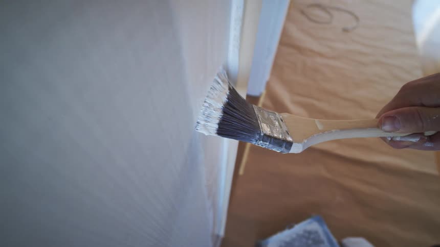 A person is painting the wall white