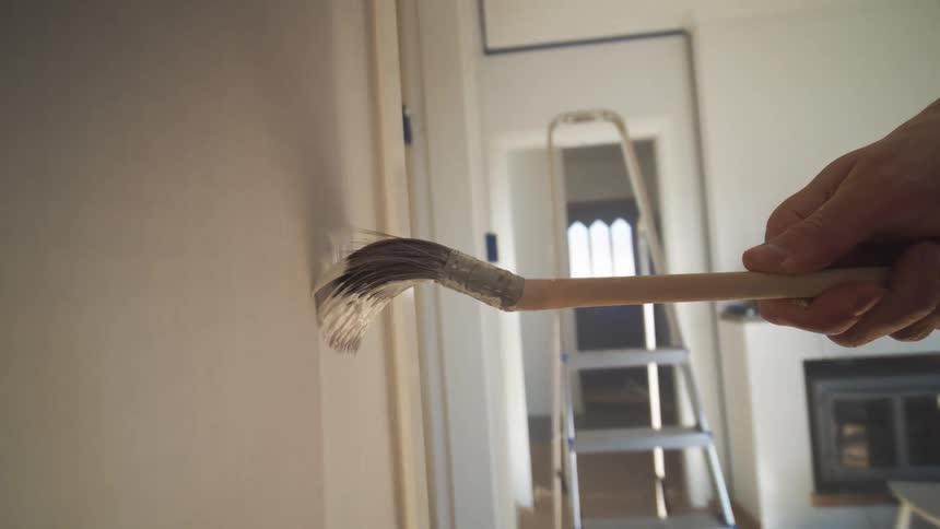 Point of view painting an interior wall with upward and downward brush strokes