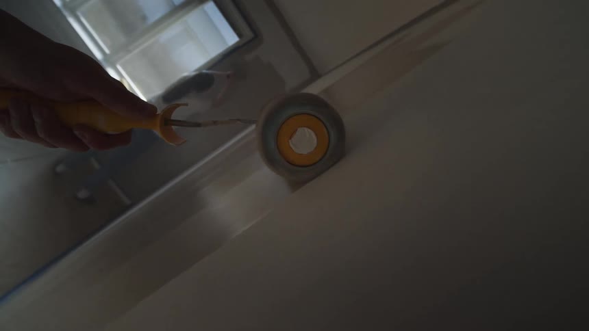 Person with a paint roller painting a wall