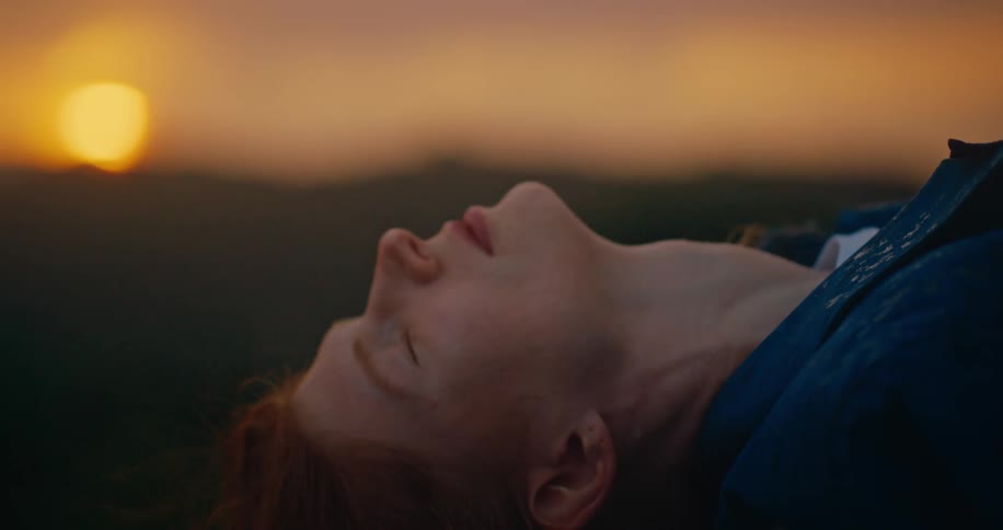 A woman leans back at sunrise