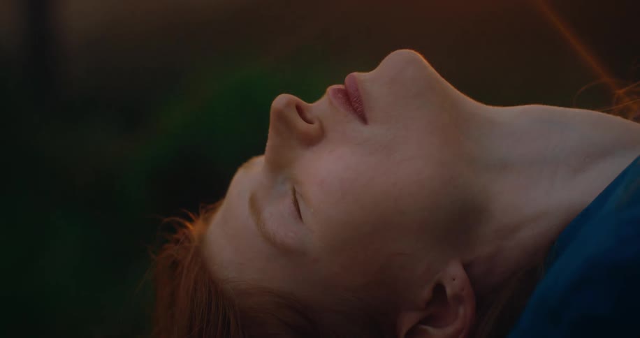 A woman leans her head back under the sunlight