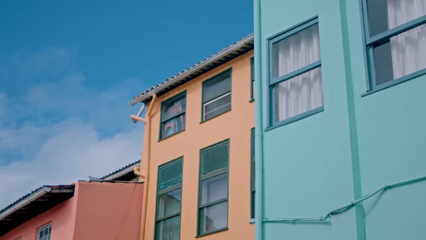 A lowangle shot looks up at a row of colorful yellow and blue apartment buildings against a bright blue sky