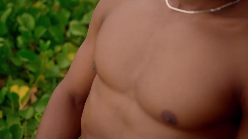 Chest of a shirtless man seated outdoor at daytime