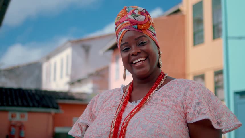 A woman happily stands outside some bright buildings