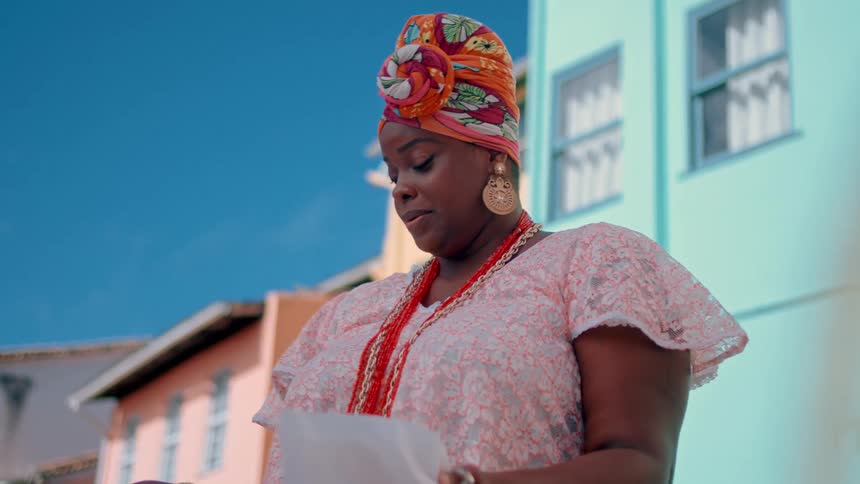 Woman reading a document while wearing traditional clothing outdoors