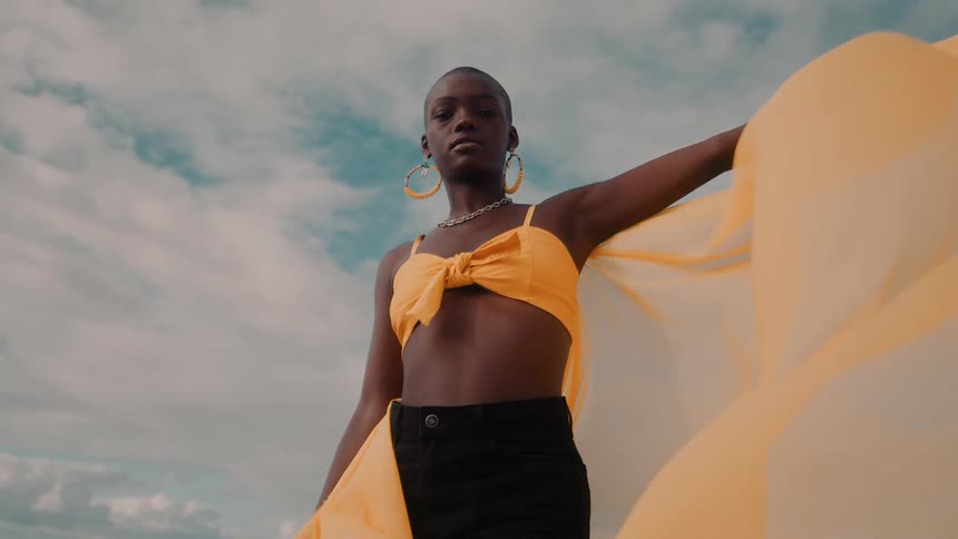 A woman with a yellow cape billowing around her
