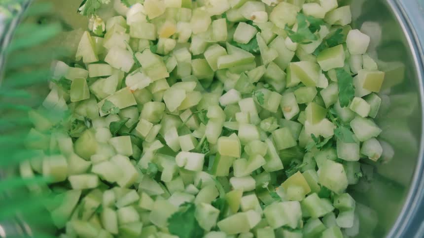 Several square pieces of cut green vegetables in a round metal container