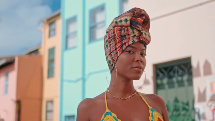 A stylish woman poses confidently outdoors in front of colorful buildings