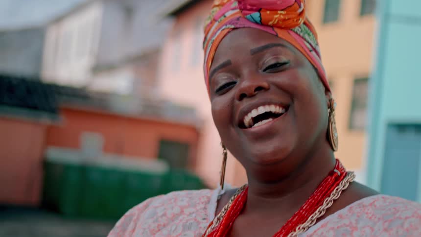A woman is laughing and smiling outdoors during the daytime