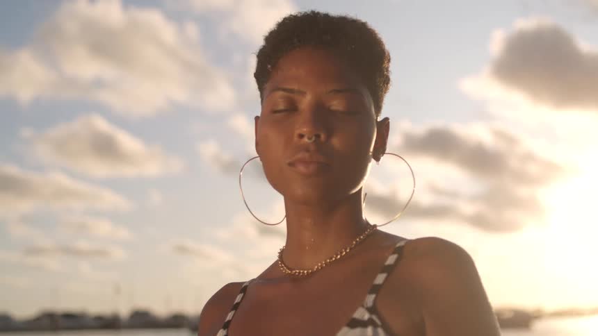 Face of a lady standing at the beach blinking eyes at daytime