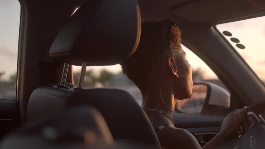 A woman sits in her car rocking her head back and forth