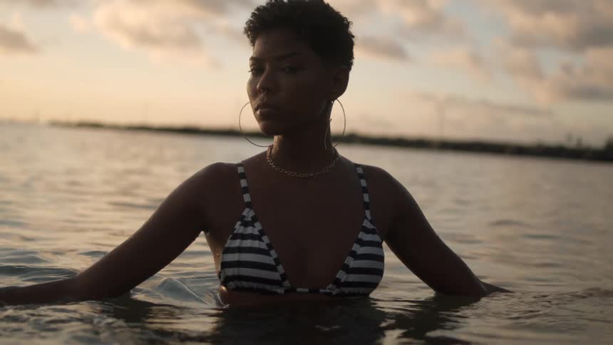 A woman swimming in ocean water while the sun is setting