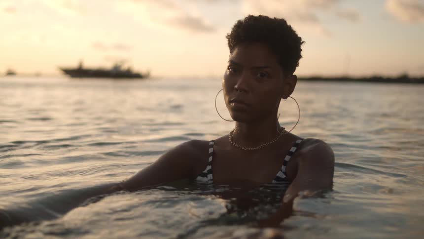A woman is swimming in the lake while the sun is setting
