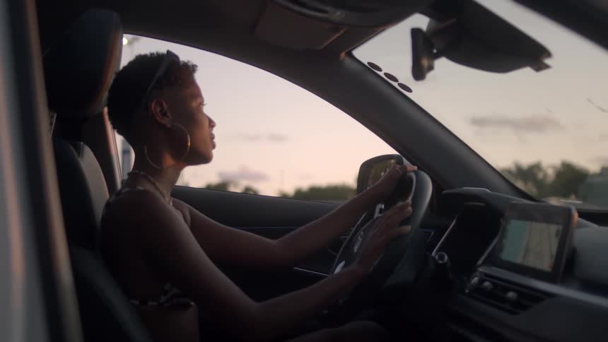 Woman sings while sitting in the drivers seat of a parked car