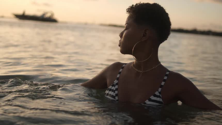 Woman is wearing jewelry and swimming in ocean water
