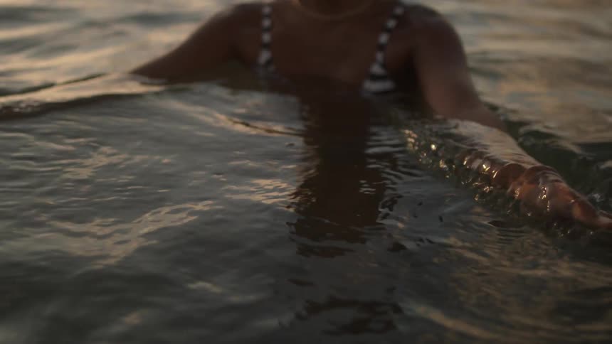 The woman waves her hands through the water