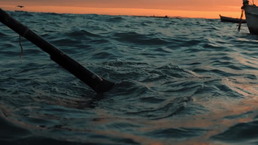 People are boating on ocean water while the sun is setting